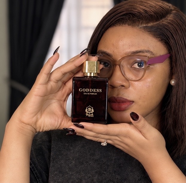 Faith holding Beguile by Omaa Goddess perfume up to her face